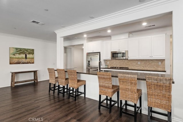 kitchen featuring appliances with stainless steel finishes, white cabinetry, sink, a breakfast bar area, and dark wood-type flooring