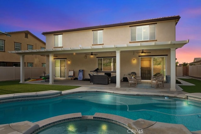 back house at dusk with ceiling fan, a swimming pool with hot tub, and a patio area