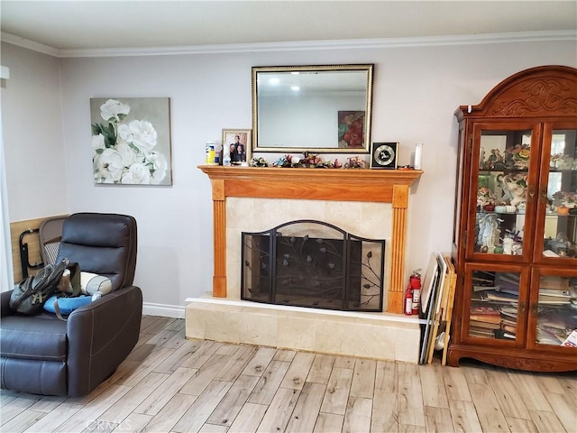 living area with ornamental molding, a fireplace, and light wood-type flooring