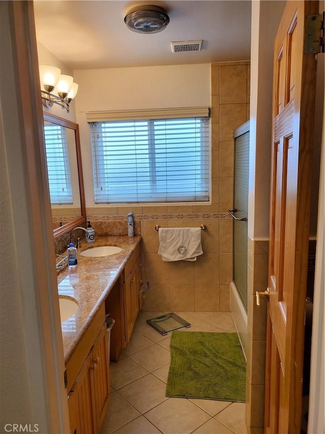 bathroom featuring tile patterned floors, vanity, combined bath / shower with glass door, and tile walls