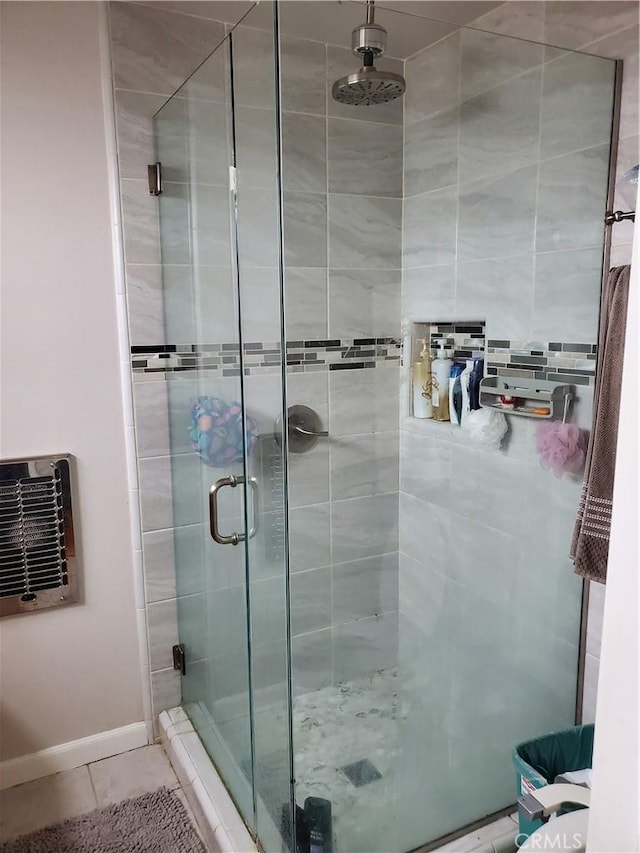 bathroom featuring heating unit, tile patterned floors, and a shower with door