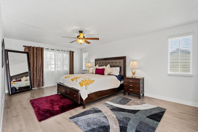 bedroom with ceiling fan, multiple windows, and light hardwood / wood-style flooring