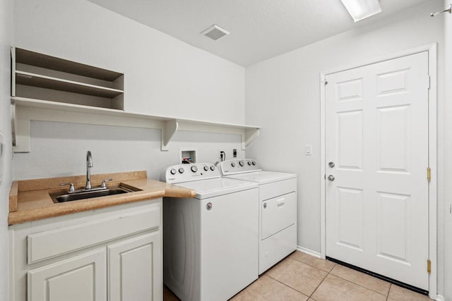 laundry area with cabinets, sink, light tile patterned floors, and washer and clothes dryer