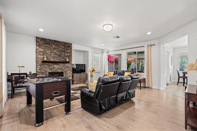 living room featuring a stone fireplace and light hardwood / wood-style floors