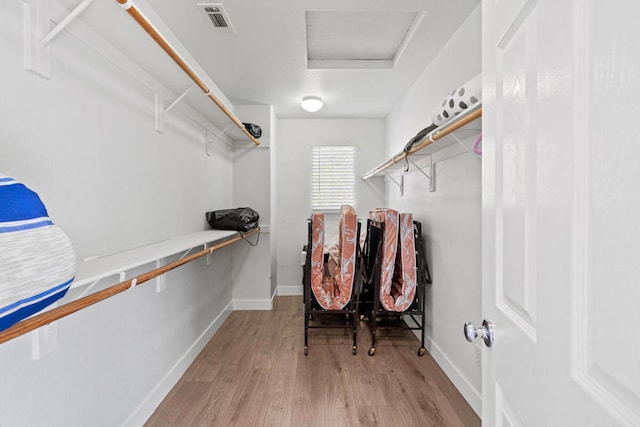 walk in closet with light hardwood / wood-style floors