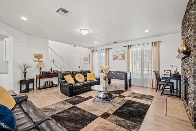 living room featuring a stone fireplace and light hardwood / wood-style floors