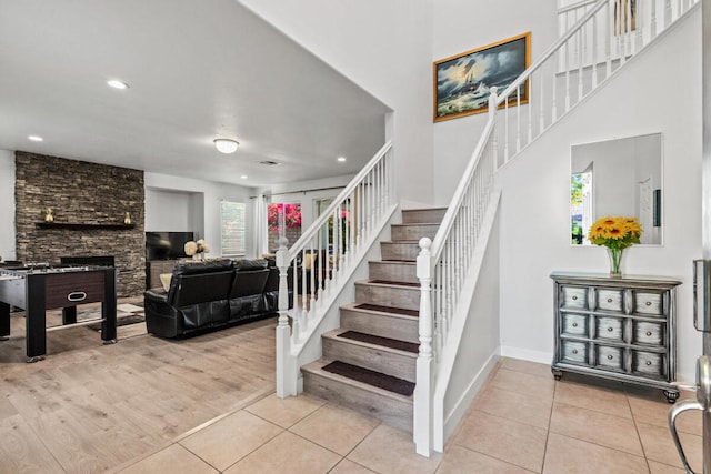 stairs with a stone fireplace, tile patterned flooring, and a high ceiling