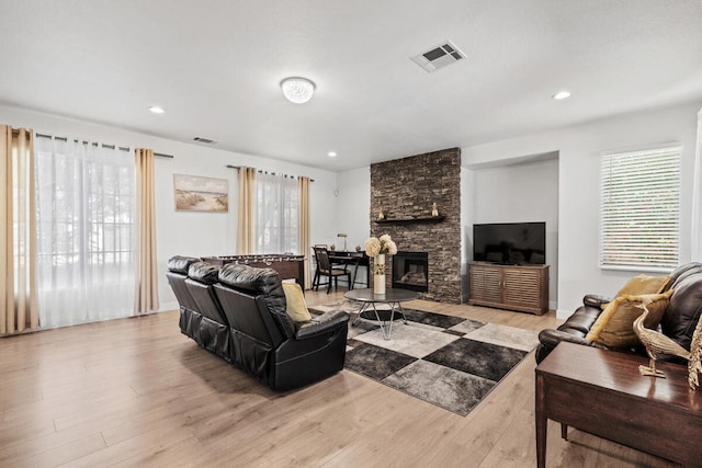 living room with a stone fireplace and light hardwood / wood-style flooring