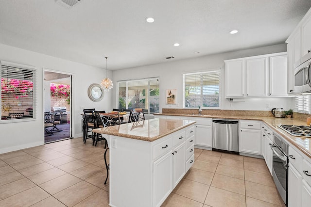 kitchen with white cabinetry, decorative light fixtures, a center island, and appliances with stainless steel finishes