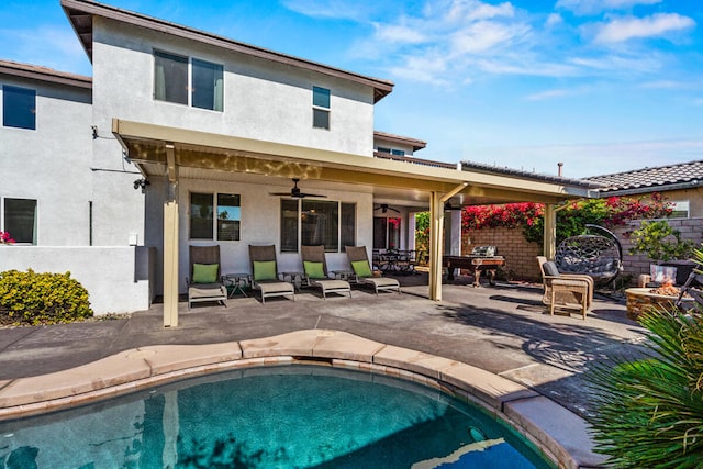 rear view of house with a fenced in pool, a patio area, ceiling fan, and an outdoor fire pit