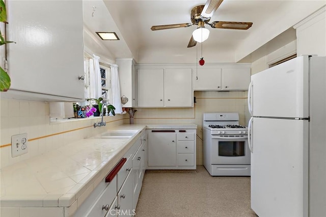 kitchen featuring sink, white appliances, tile countertops, and white cabinets