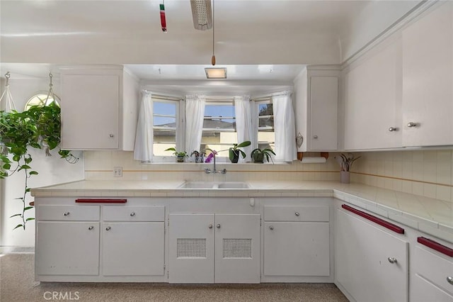 kitchen featuring white cabinets, sink, tile counters, and decorative backsplash