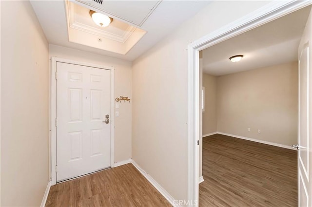 entryway featuring a raised ceiling, crown molding, and dark wood-type flooring