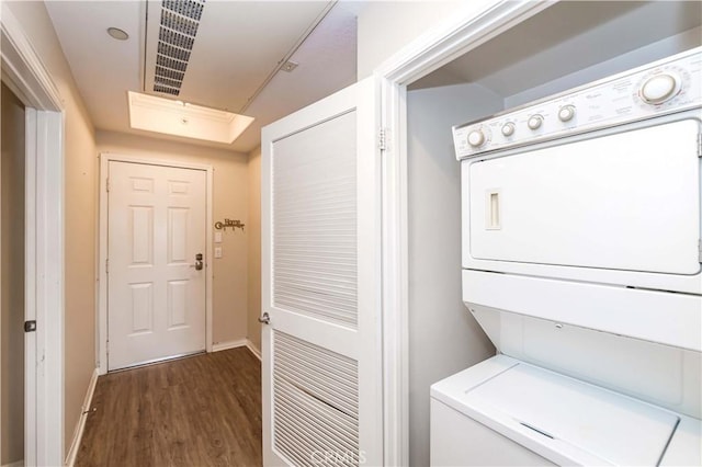 clothes washing area featuring stacked washer / dryer and dark hardwood / wood-style flooring