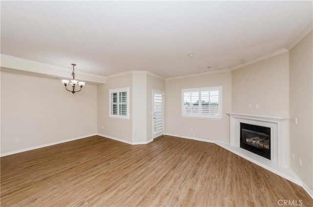 unfurnished living room featuring a notable chandelier, crown molding, and wood-type flooring