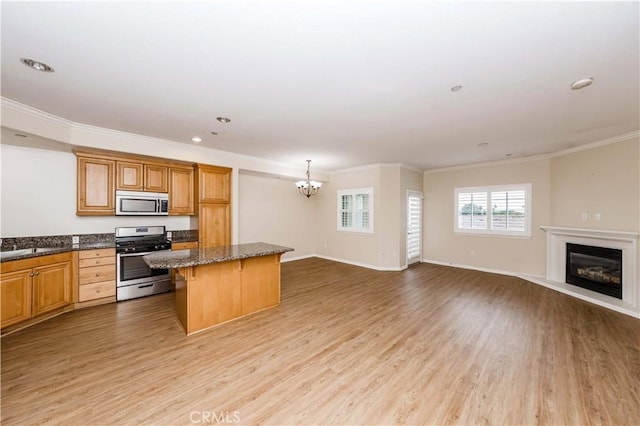 kitchen with a breakfast bar area, crown molding, a center island, light wood-type flooring, and stainless steel appliances