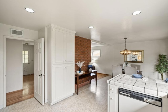 kitchen with decorative light fixtures, a chandelier, tile countertops, dishwasher, and white cabinets