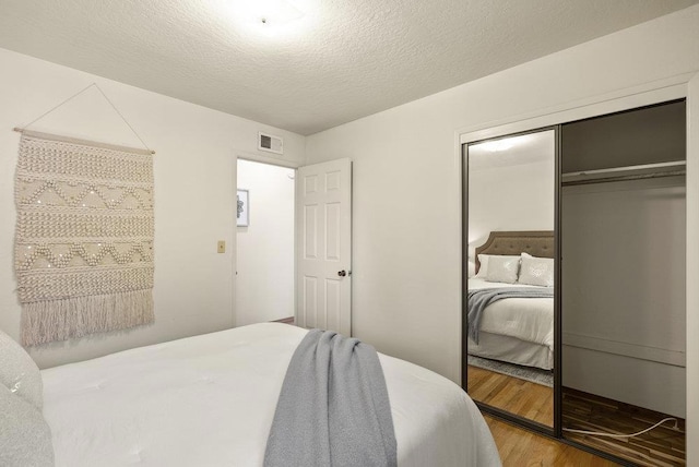 bedroom with hardwood / wood-style floors, a textured ceiling, and a closet