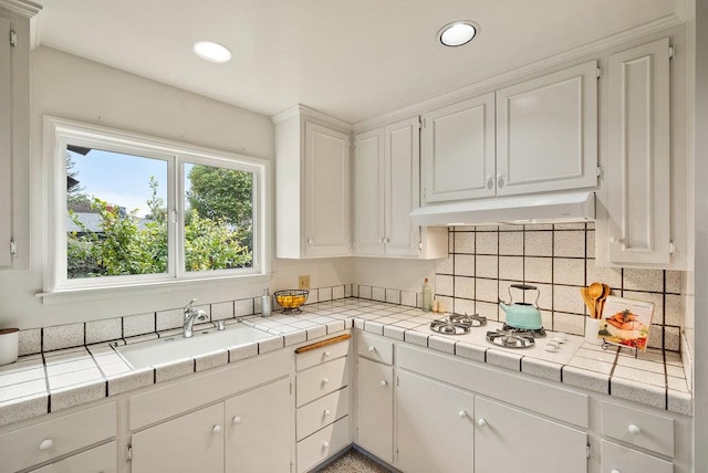 kitchen with sink, tile countertops, and white cabinets