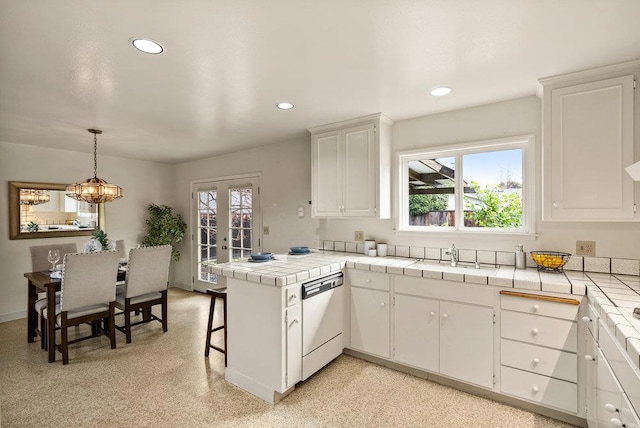 kitchen with tile counters, dishwasher, kitchen peninsula, and white cabinets