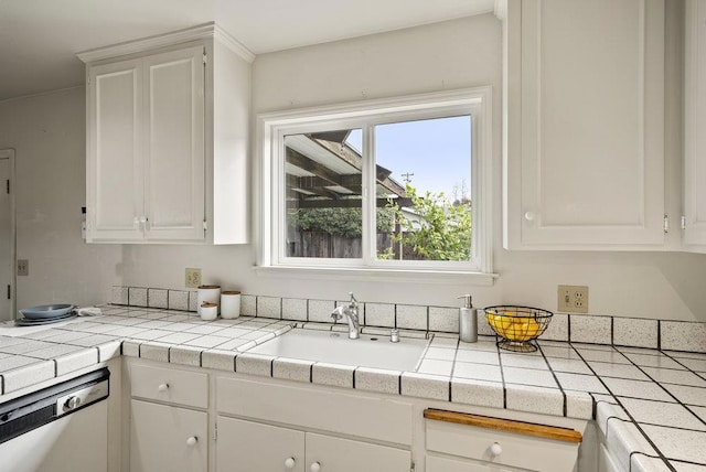 kitchen with white cabinetry, dishwasher, sink, and tile counters