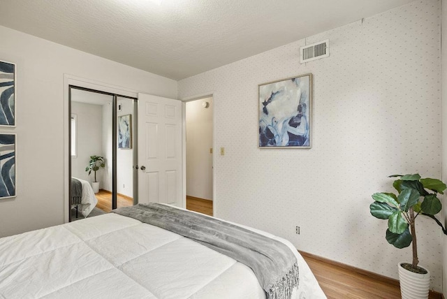 bedroom featuring hardwood / wood-style floors, a closet, and a textured ceiling