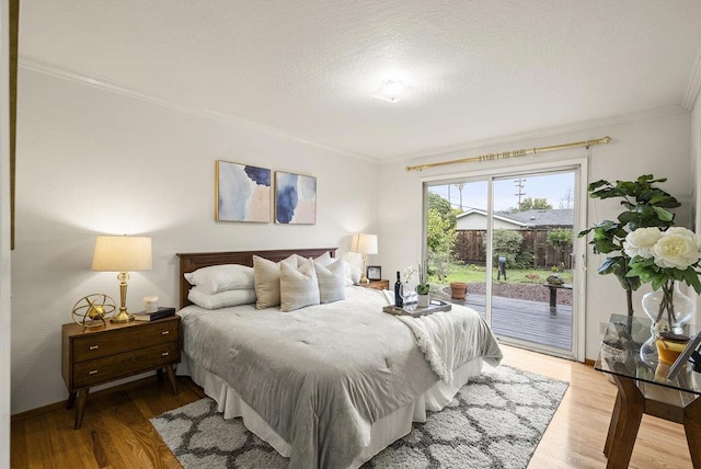 bedroom featuring ornamental molding, light hardwood / wood-style floors, a textured ceiling, and access to outside