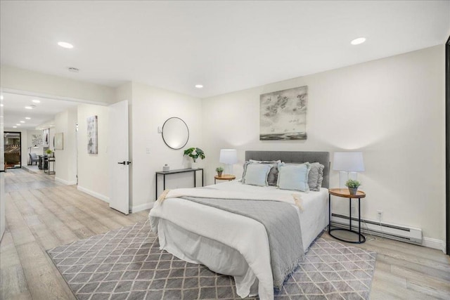 bedroom with light wood-type flooring and a baseboard heating unit