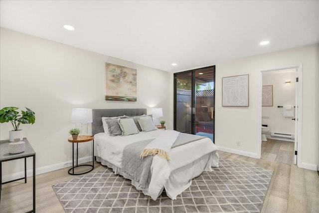 bedroom with ensuite bath, access to exterior, light wood-type flooring, and a baseboard heating unit