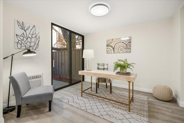 home office featuring a wall of windows, light hardwood / wood-style flooring, and an AC wall unit