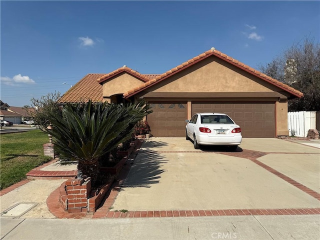 view of front facade featuring driveway, an attached garage, a tiled roof, and stucco siding