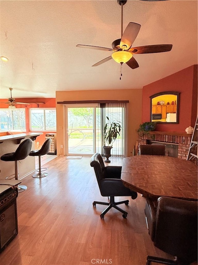 home office featuring a ceiling fan, light wood-style flooring, and a textured ceiling