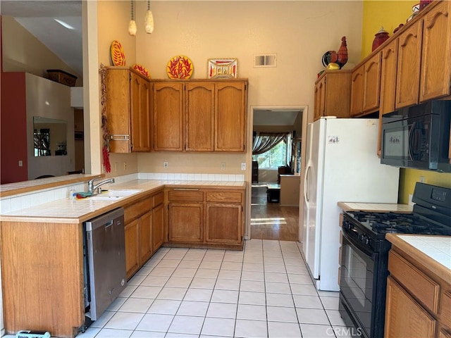 kitchen with tile counters, visible vents, brown cabinetry, a sink, and black appliances