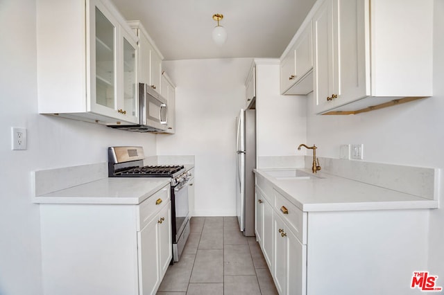 kitchen featuring stainless steel appliances, white cabinetry, sink, and light tile patterned floors