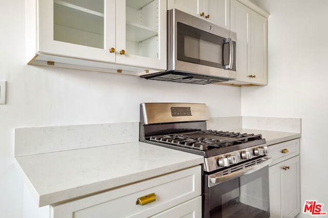 kitchen featuring light stone counters, white cabinets, and appliances with stainless steel finishes