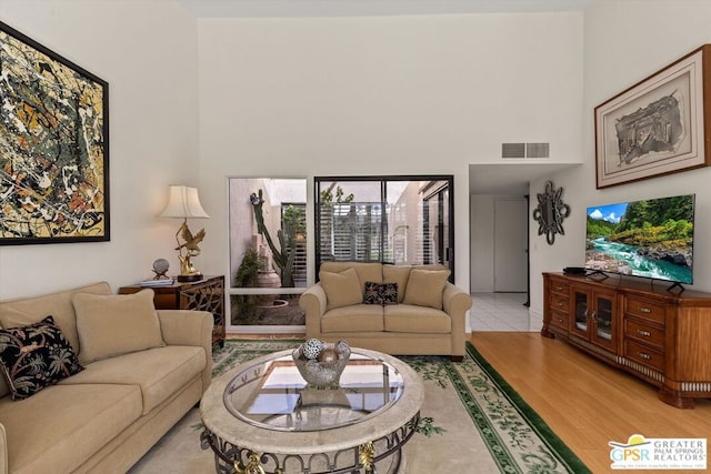 living room featuring light wood-type flooring and a high ceiling