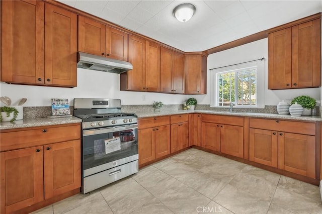 kitchen featuring gas range, sink, and light stone counters