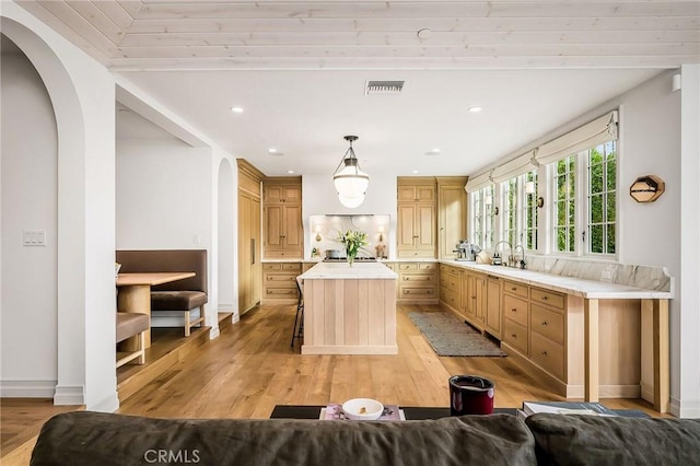 kitchen featuring hanging light fixtures, a kitchen island, a breakfast bar, and light hardwood / wood-style floors