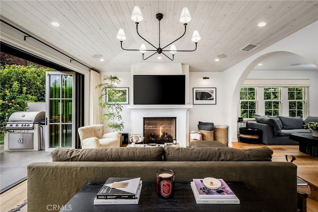 living room featuring an inviting chandelier, lofted ceiling, hardwood / wood-style floors, and wooden ceiling