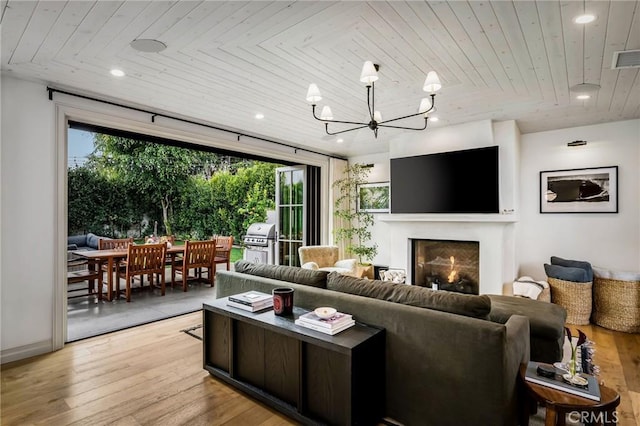 living room with a notable chandelier, wood ceiling, and light hardwood / wood-style floors