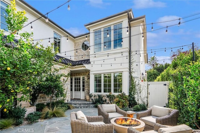 rear view of property with an outdoor living space with a fire pit and a patio