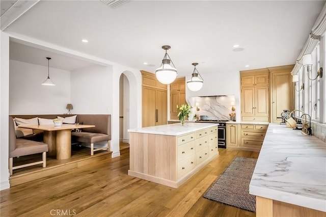 kitchen featuring high end range, light brown cabinetry, pendant lighting, and a center island