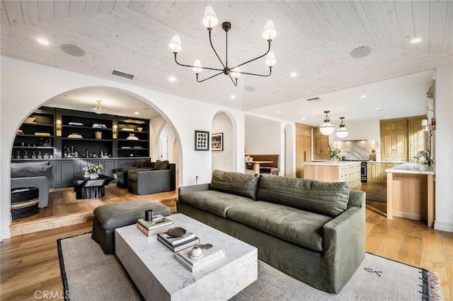 living room with lofted ceiling, light hardwood / wood-style flooring, built in features, an inviting chandelier, and wooden ceiling