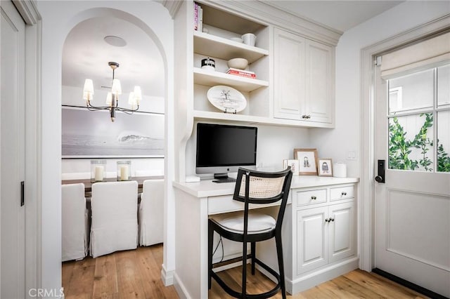 office with a notable chandelier, built in desk, and light hardwood / wood-style floors