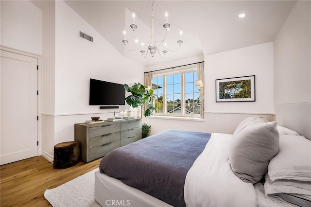 bedroom featuring vaulted ceiling, light hardwood / wood-style flooring, and a notable chandelier