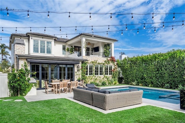 back of property with a patio, a balcony, a yard, and outdoor lounge area