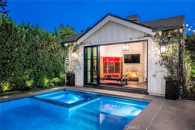 view of pool featuring an in ground hot tub, an outbuilding, and a patio