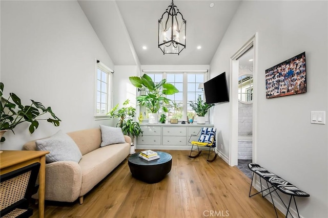 sitting room with vaulted ceiling, light hardwood / wood-style floors, and a notable chandelier