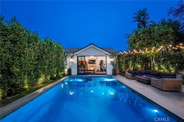 pool at twilight with an outdoor structure, outdoor lounge area, and a patio area