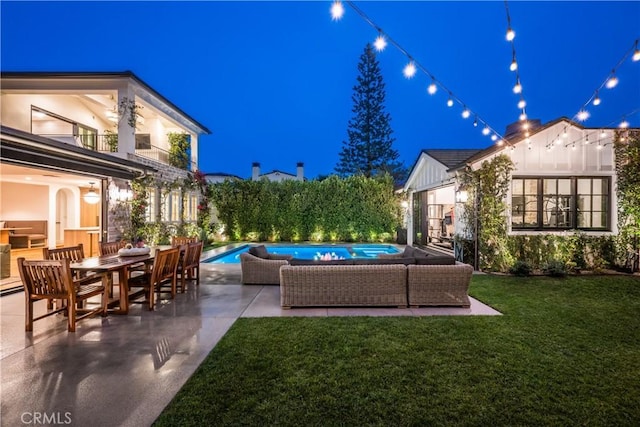 patio at night featuring a balcony, a yard, and an outdoor hangout area